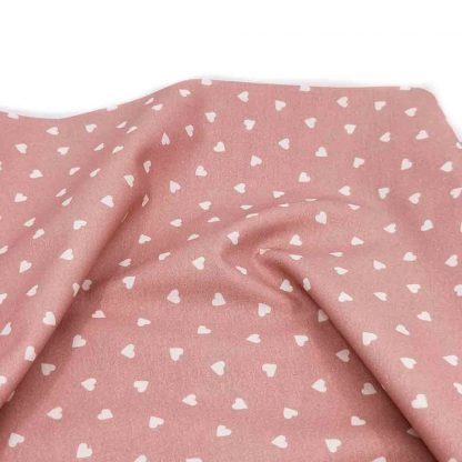 Tela de popelín de algodón orgánico estampado con corazones sobre fondo rosa palo