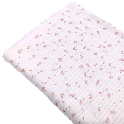 Tela serker de algodón orgánico estampada con flores pequeñas de color rosa