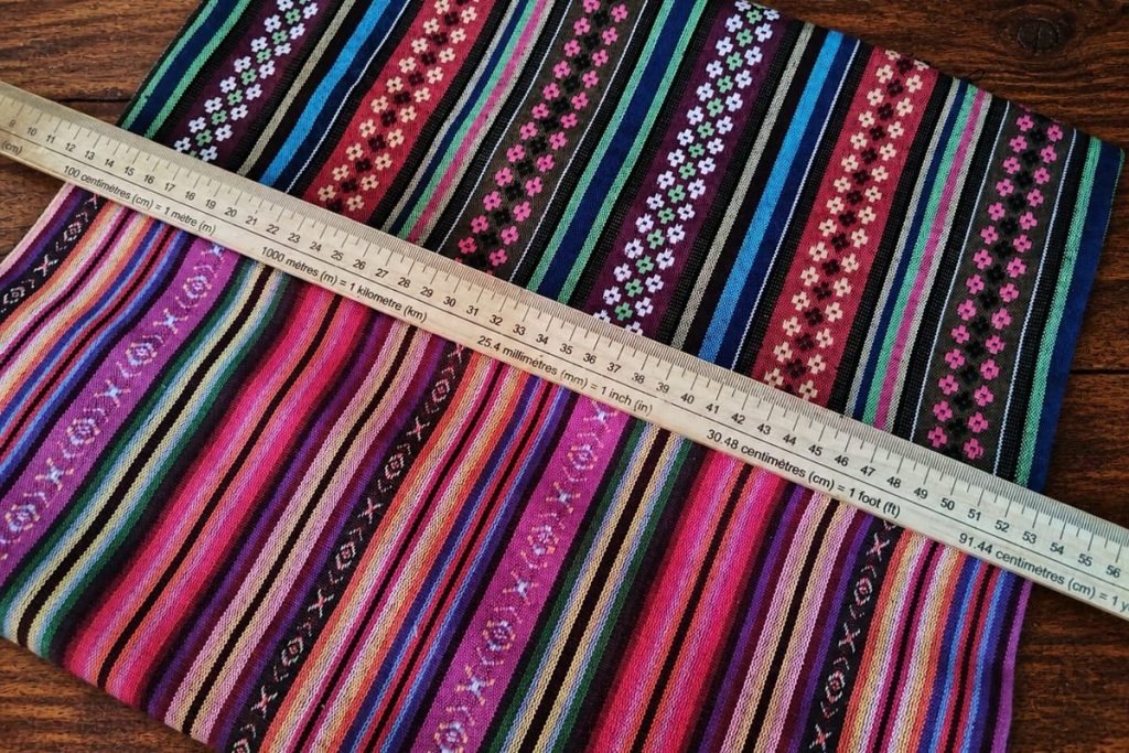 Dos telas alpujarreñas extendidas junto a una regla métrica sobre una mesa de madera